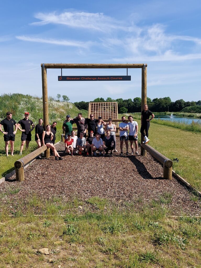 Group of people posing infront of assualt course