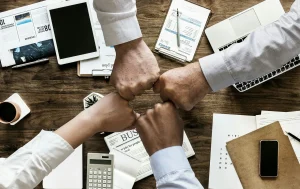 Four fists pumping over a meeting room table