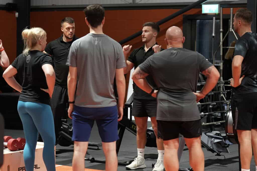 Gym members and personal trainers talking