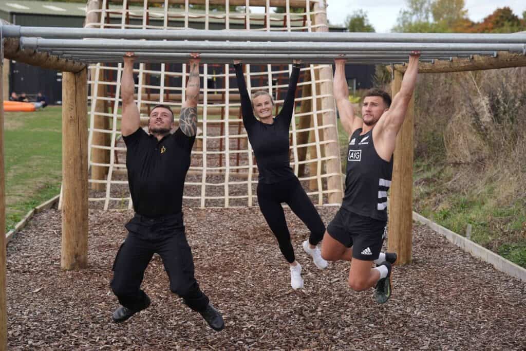 bicester gym team members using monkey bars on assault course - team building activities in oxford